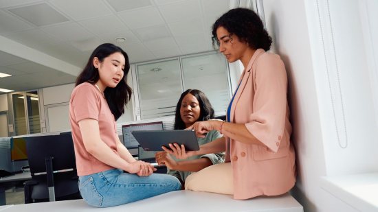 Three women at meeting looking at tablet computer