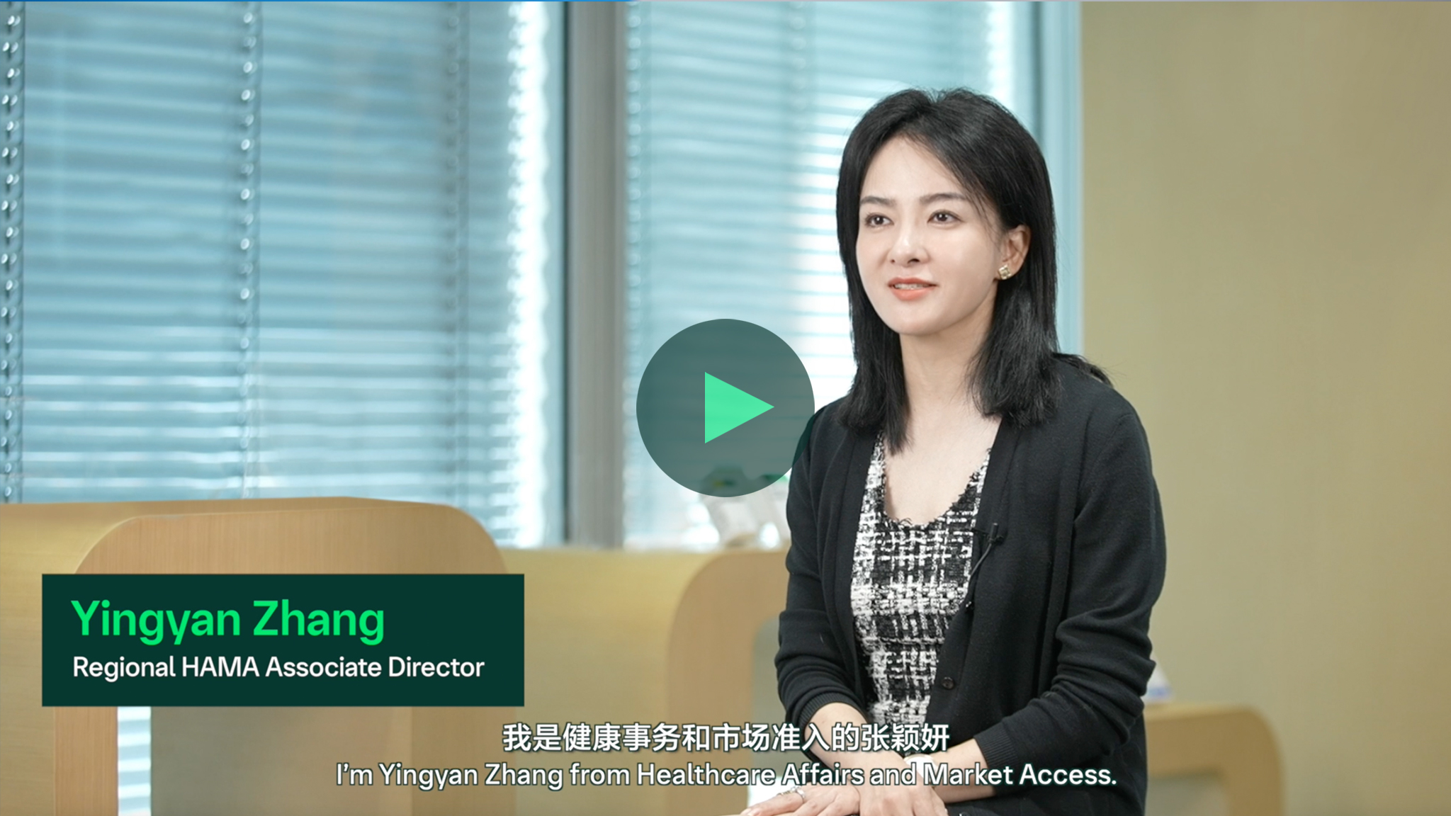 室内拍摄，一位人物坐着接受采访，背景有彩色圆形图案，画面中有播放按钮。