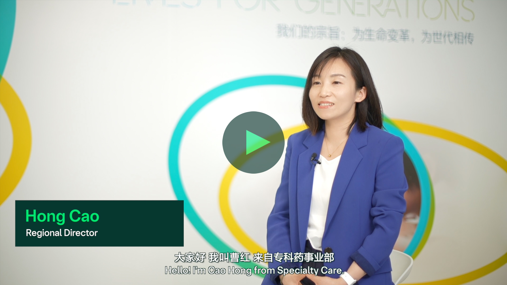 室内拍摄，一位人物坐着接受采访，背景有彩色圆形图案，画面中有播放按钮。